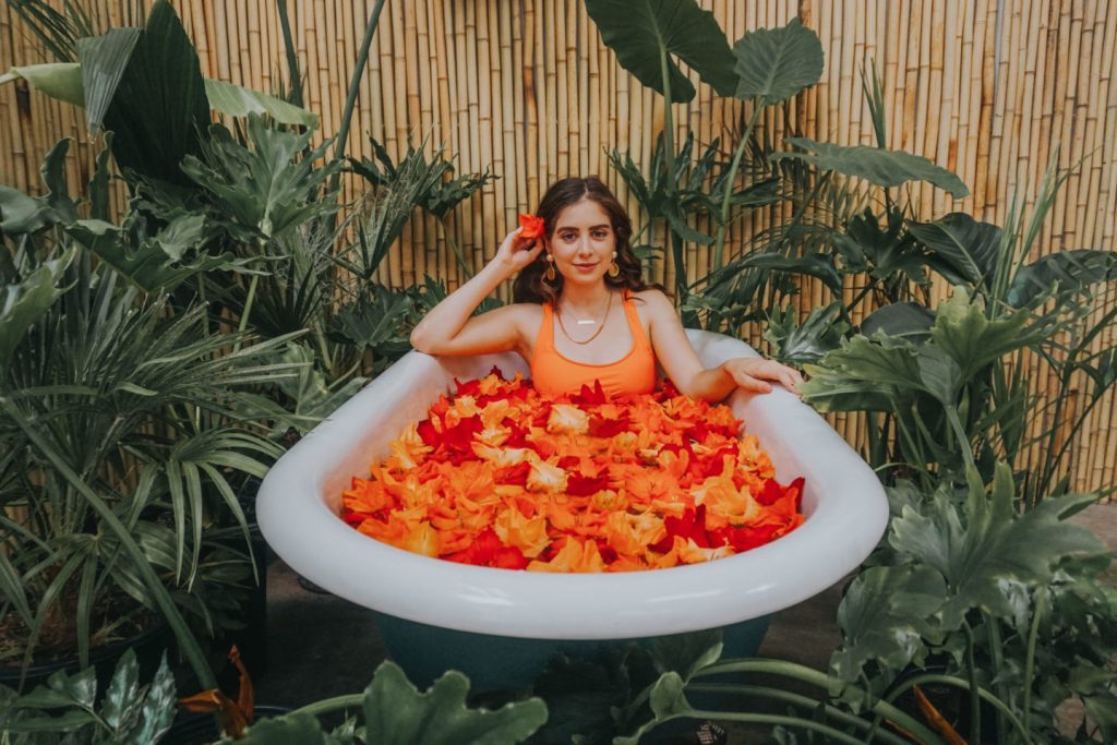 Woman relaxing in a bathtub filled with orange flower petals at a luxurious Sri Lankan resort.