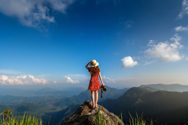 Discover the magic of Sri Lanka with Gleam Pearl Tours. A woman admires the scenic beauty of the mountains, a testament to the island's natural wonders.