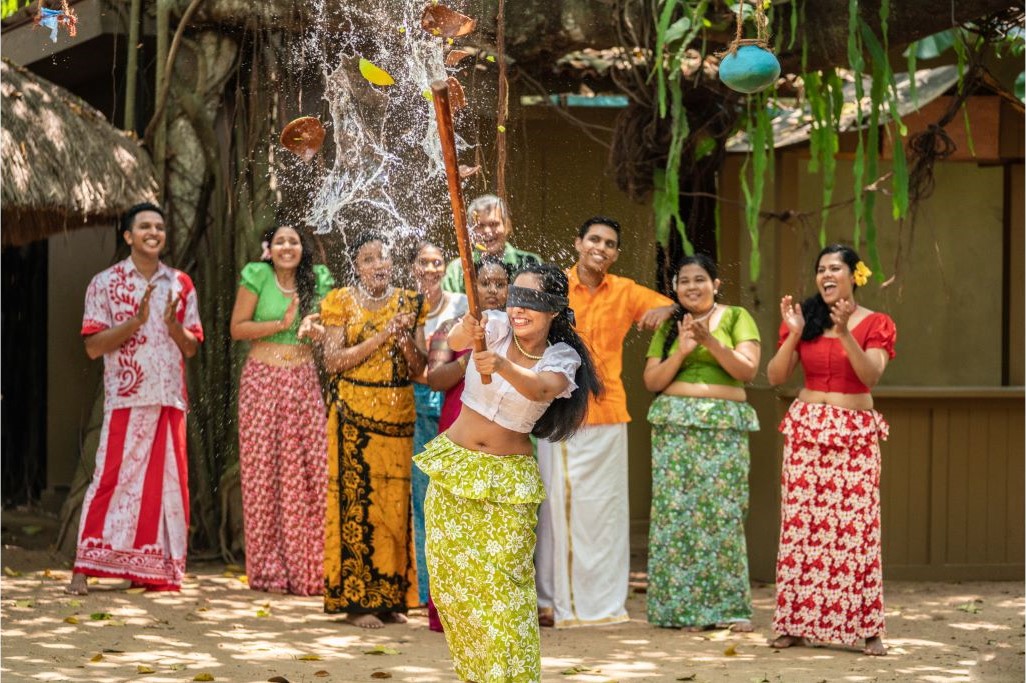 Thrills of Paradise 23 A group of friends celebrating Sinhalese New Year in Sri Lanka, with water games and traditional clothing. Book your Sri Lanka tour with Gleam Pearl Tours